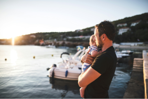 Man holding a baby by the sea