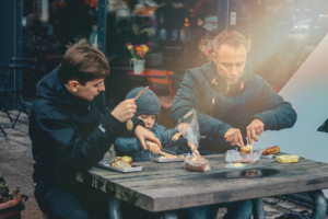 Two men at a table with a child eating