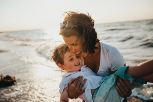 Mother hugging child by the sea